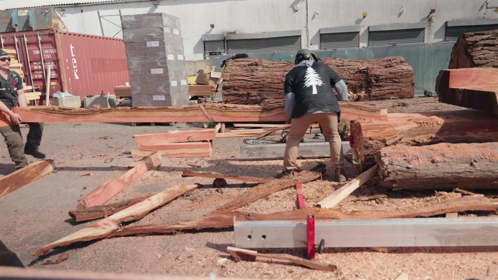 Handling timber beside the mill in a yard.